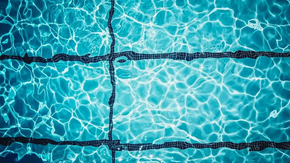 Close-up of a shimmering turquoise swimming pool surface with tile lines.
