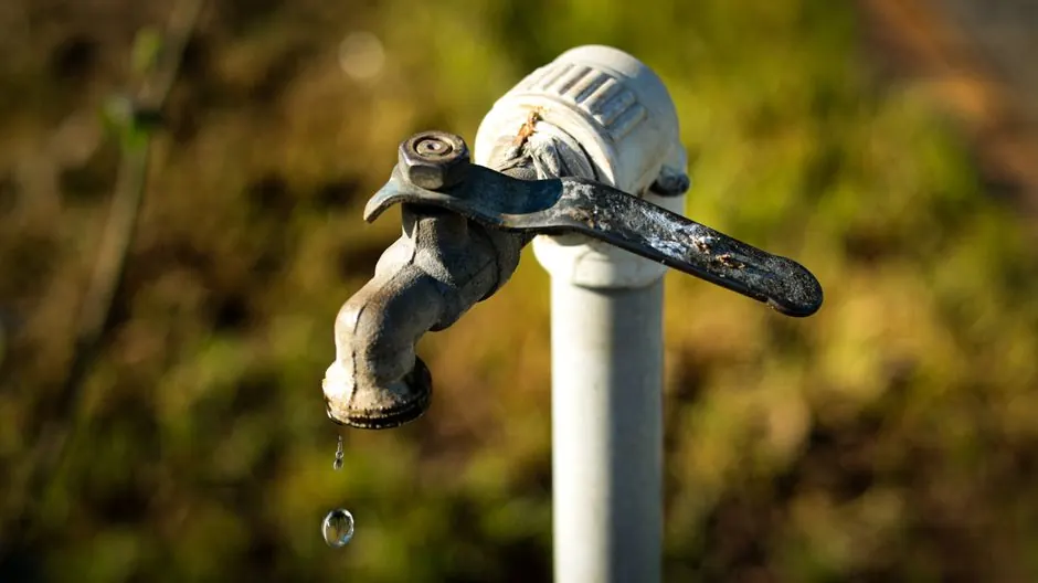Close-up of an old rusty water faucet dripping water outdoors.